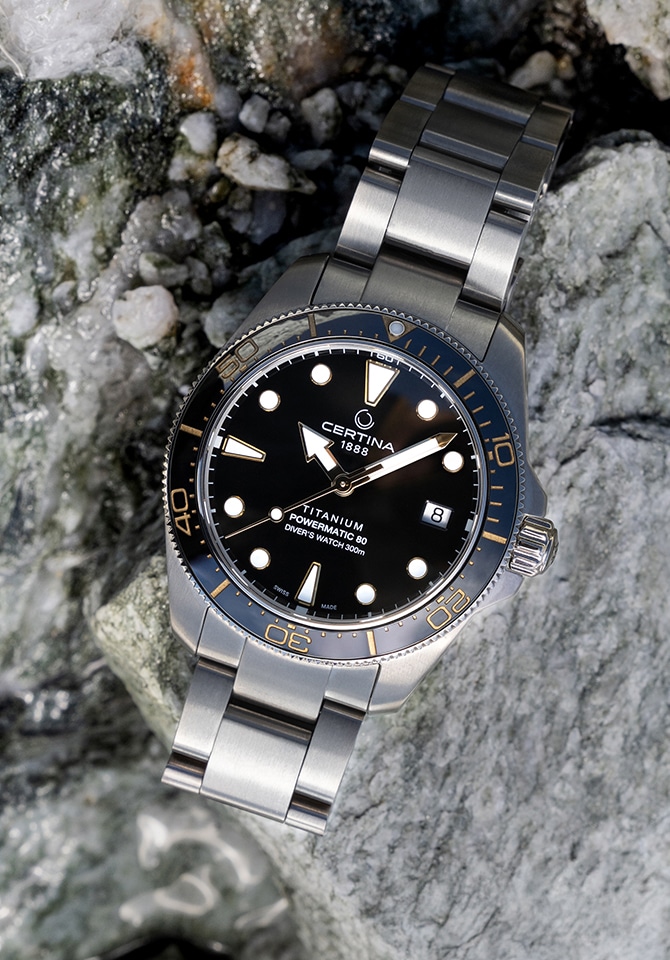 Certina DS Action Diver z czarną tarczą i stalową bransoletą na tle skał i wody