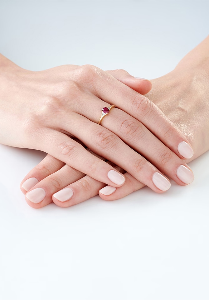 Dłonie z eleganckim pierścionkiem z czerwonym kamieniem i naturalnym manicure