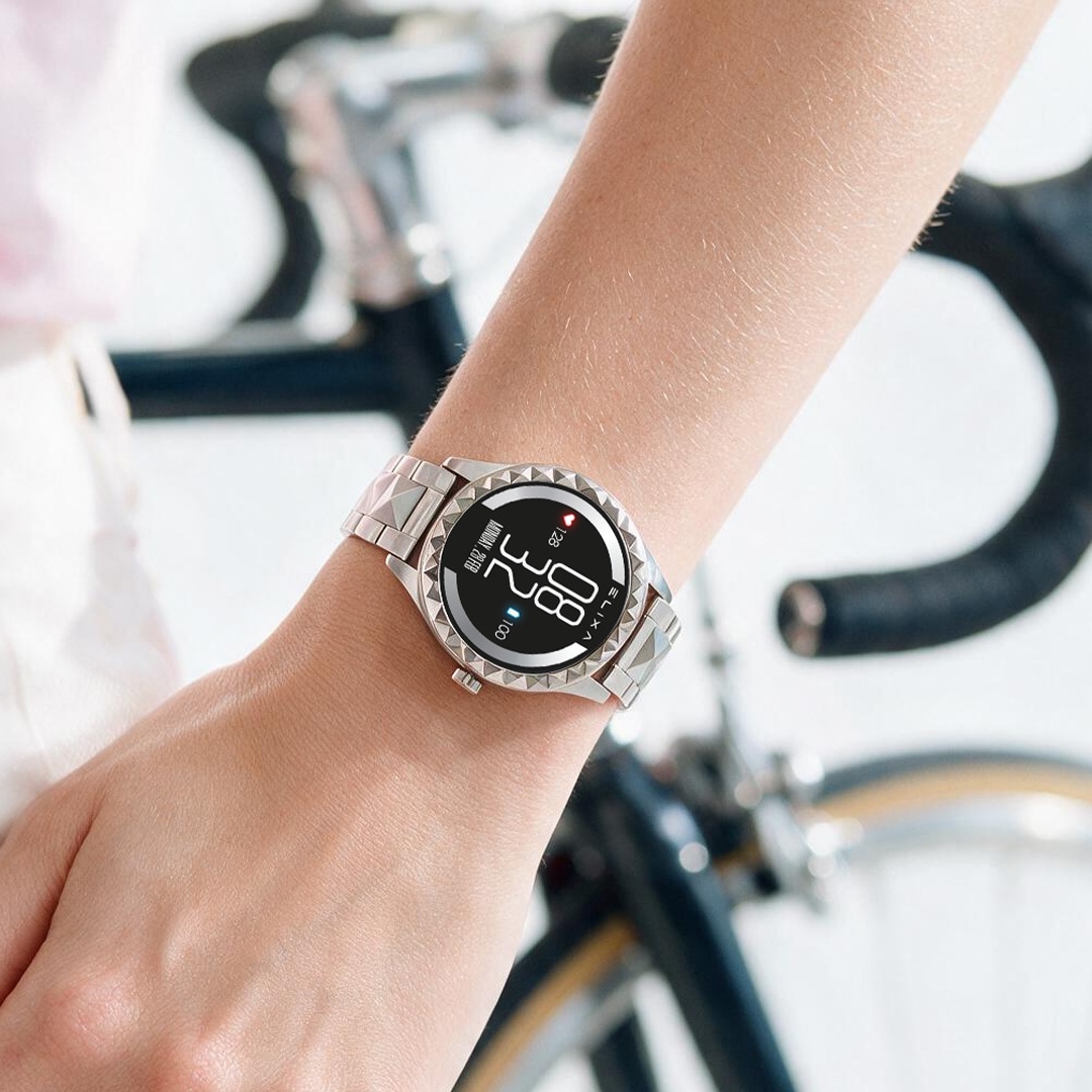 Srebrny smartwatch sportowy na nadgarstku rowerzystki podczas jazdy na rowerze